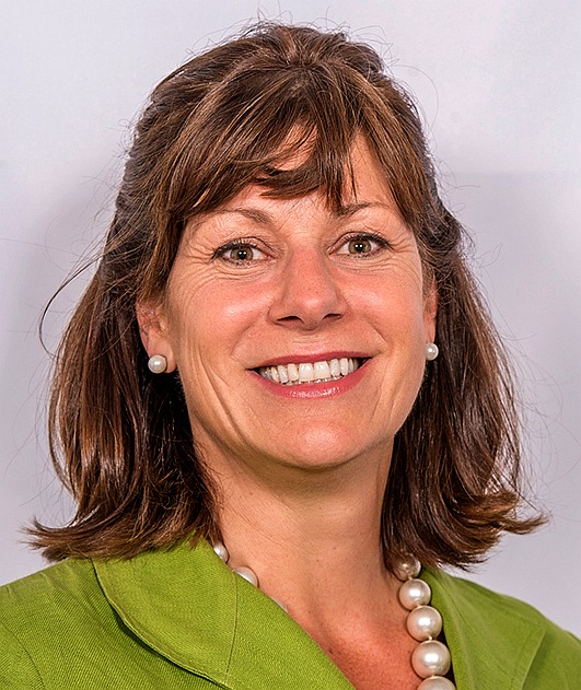 Claire Perry MP in green wearing pearls